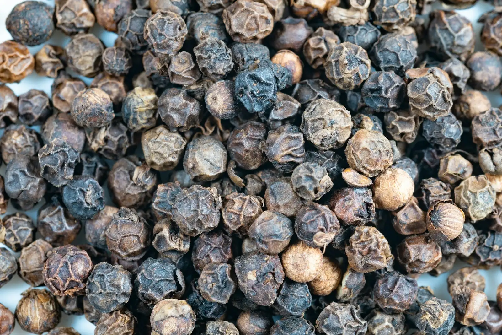 Granos de pimienta negra en primer plano, la fuente alimentaria más conocida del betacariofileno