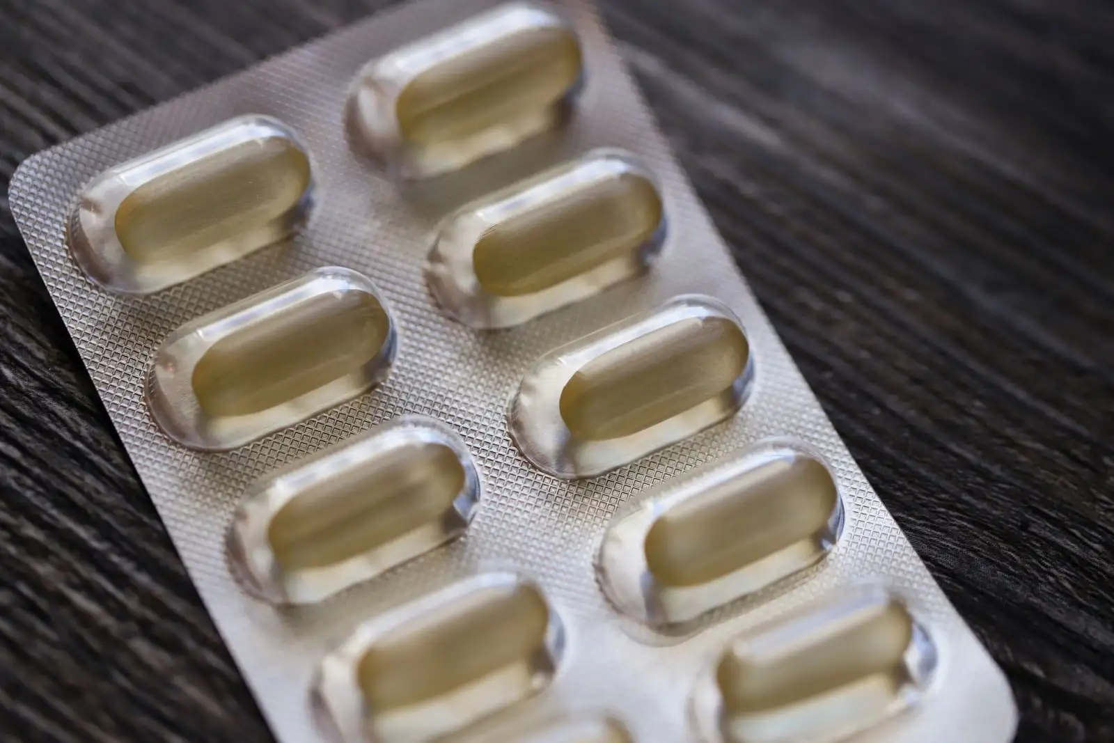 Blíster de cápsulas sobre una mesa de madera, uno de los medicamentos cuya eliminación puede modificar el CBD