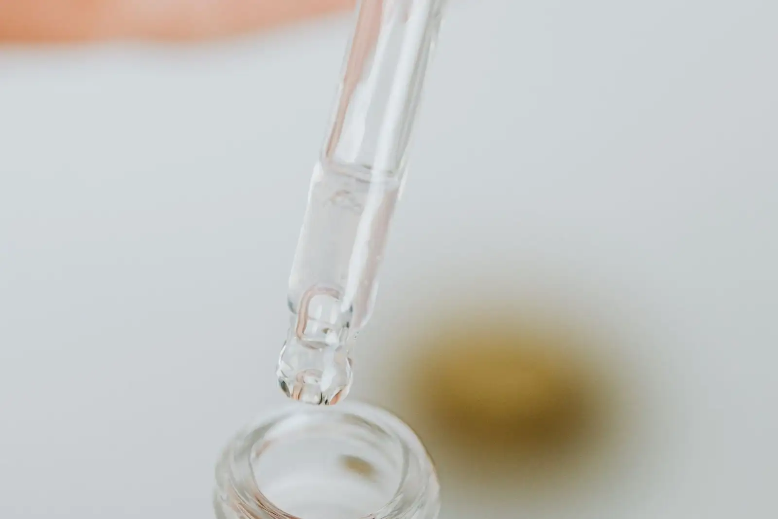 Pipeta de vidrio sobre un frasco abierto, con una gota a punto de caer