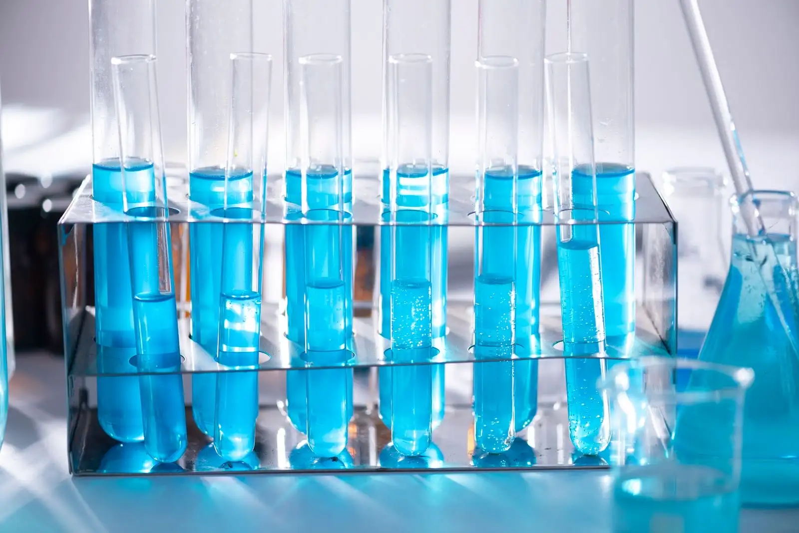 Tubos de ensayo llenos de un líquido azul alineados en una gradilla de laboratorio