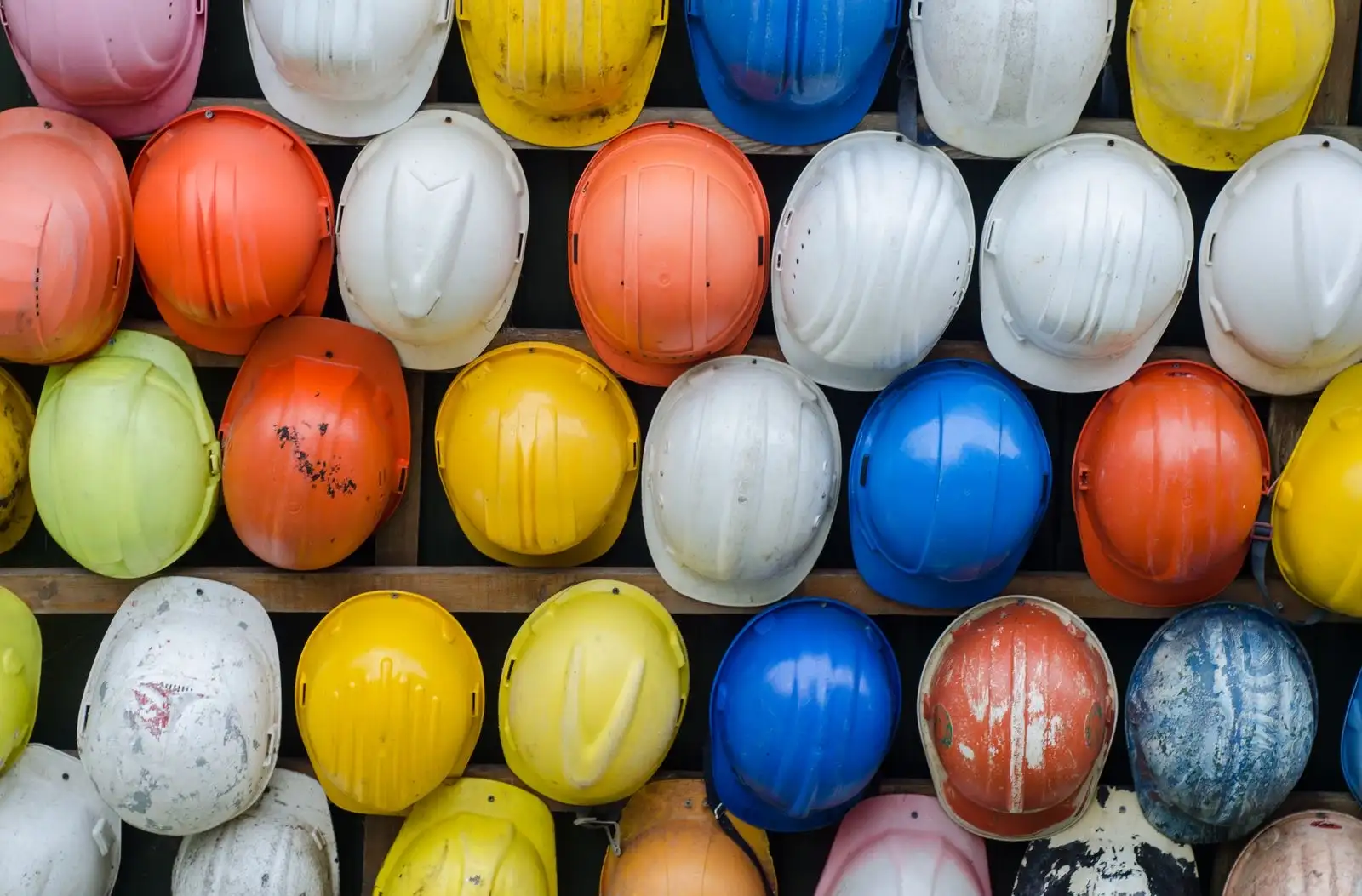 Cascos de obra de varios colores alineados en estanterías, el equipo de los puestos de riesgo donde puede preverse un test
