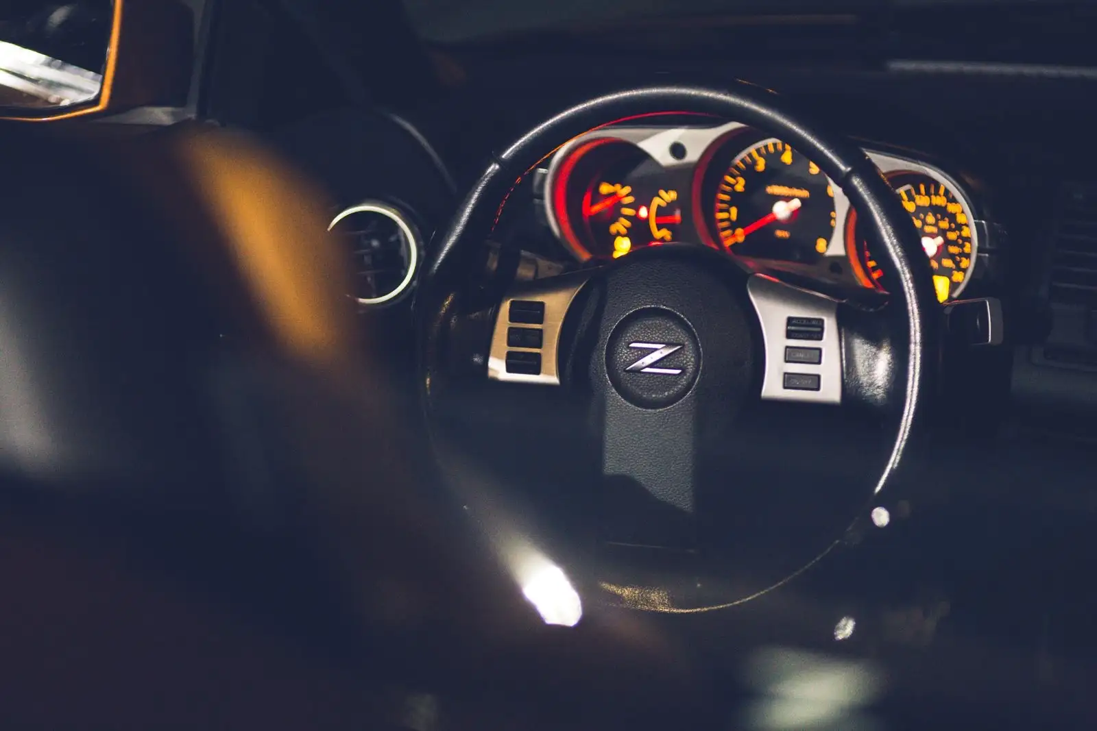 Volante y relojes iluminados de un coche de noche, vistos desde el asiento del conductor