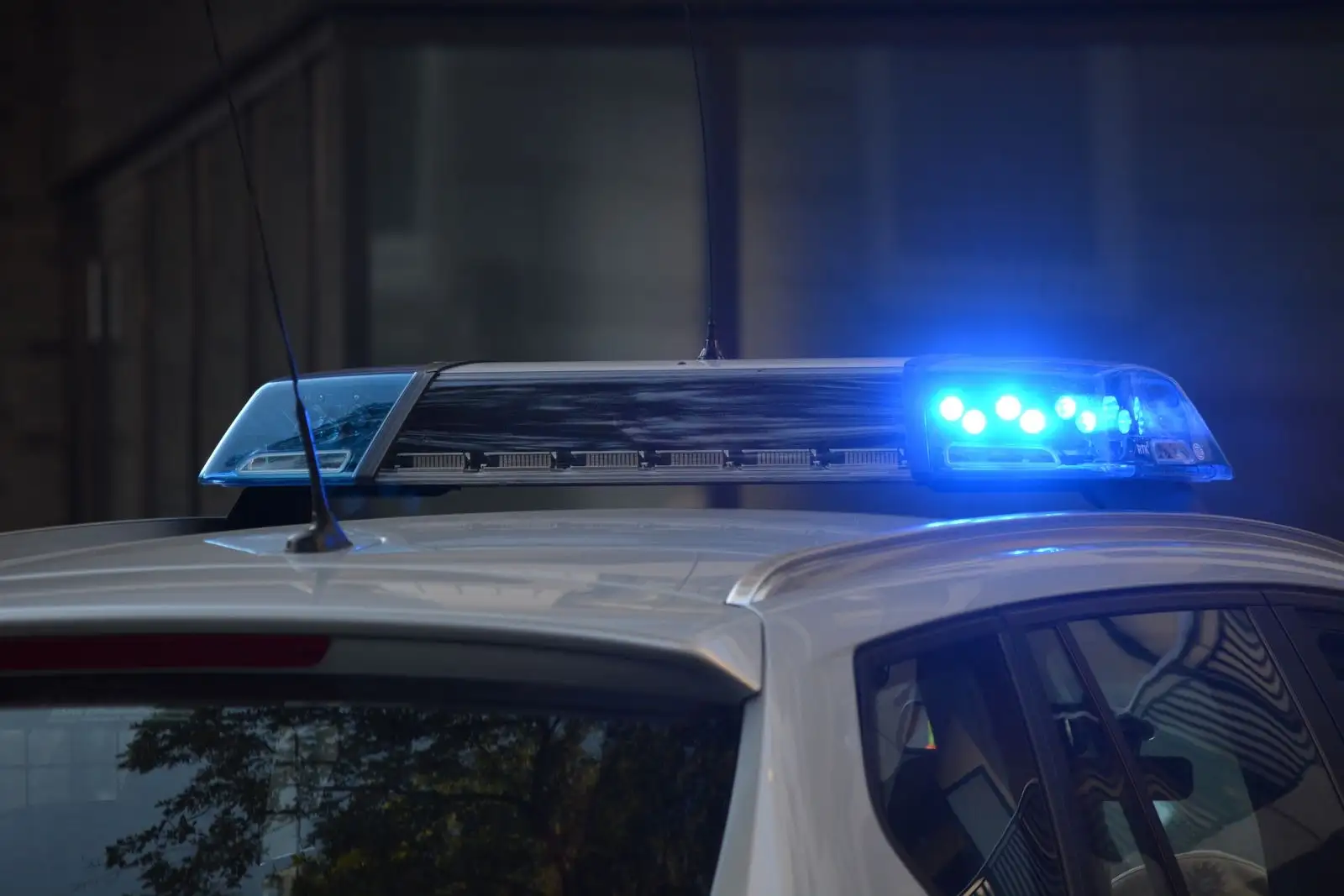 Barra de luces azules encendida en el techo de un coche de policía, de noche