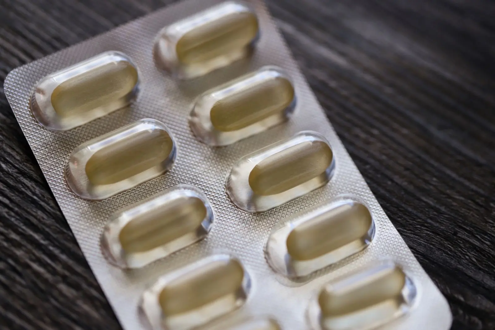Blíster de cápsulas sobre una mesa de madera, uno de los medicamentos cuya eliminación puede modificar el CBD