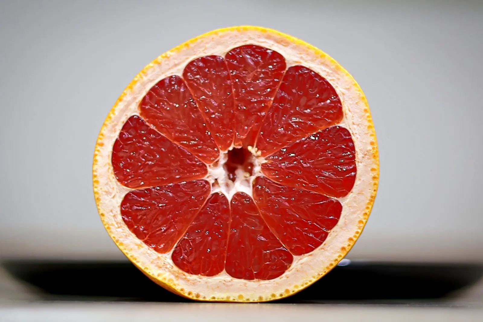 Medio pomelo rosa en primer plano, la fruta cuyas interacciones con los medicamentos son las más estudiadas