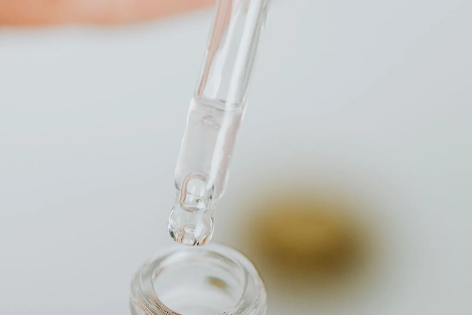 Pipeta de vidrio sobre un frasco abierto, con una gota a punto de caer