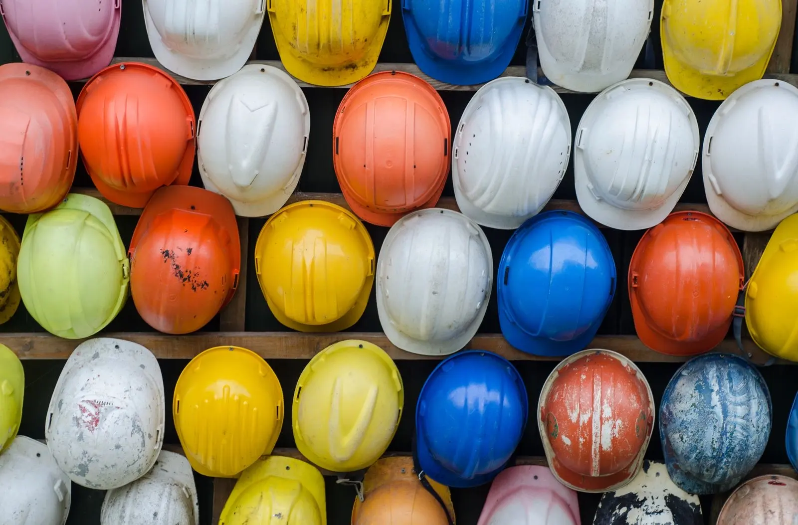 Cascos de obra de varios colores alineados en estanterías, el equipo de los puestos de riesgo donde puede preverse un test